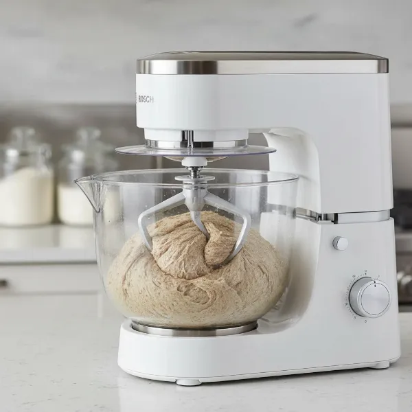 Bosch Universal Plus mixer kneading a large batch of dense bread dough in its 6.5-quart bowl.