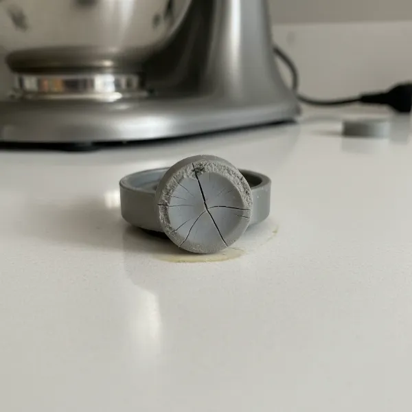Close-up of a stand mixer's base with worn, cracked rubber feet failing to grip the countertop.